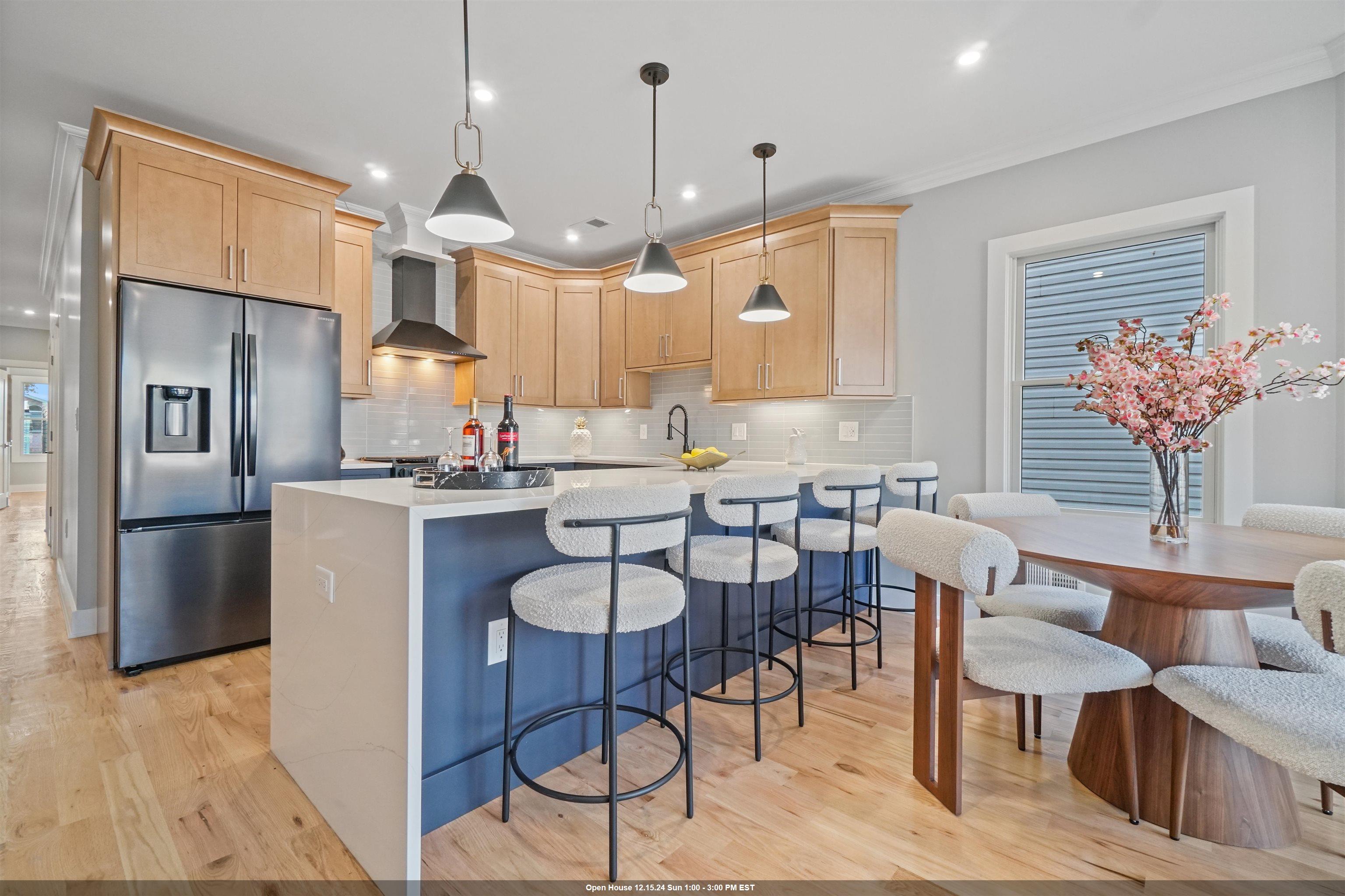 a kitchen with stainless steel appliances kitchen island granite countertop a table chairs and a refrigerator