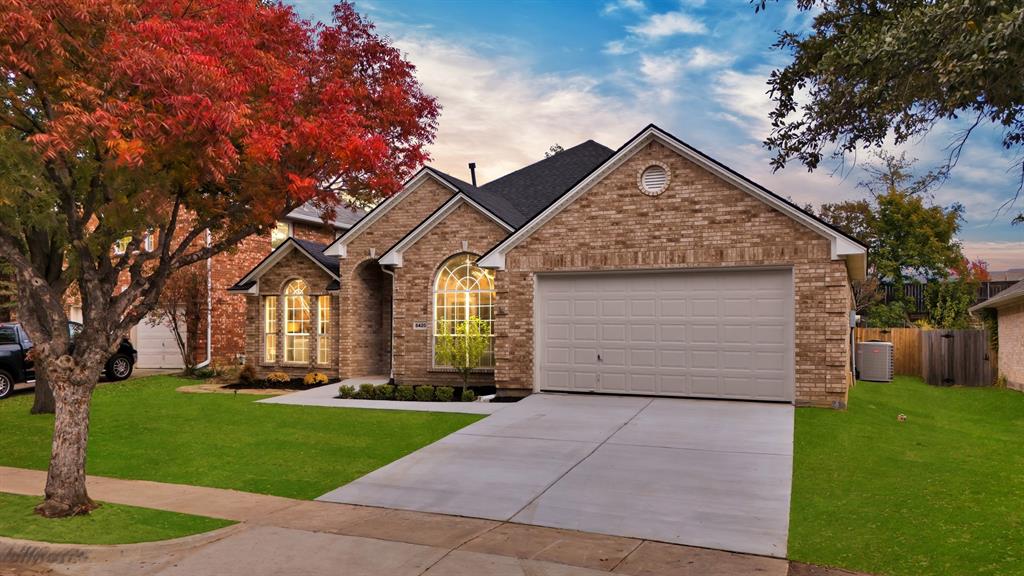 View of front of home featuring a garage, a yard, and central air condition unit