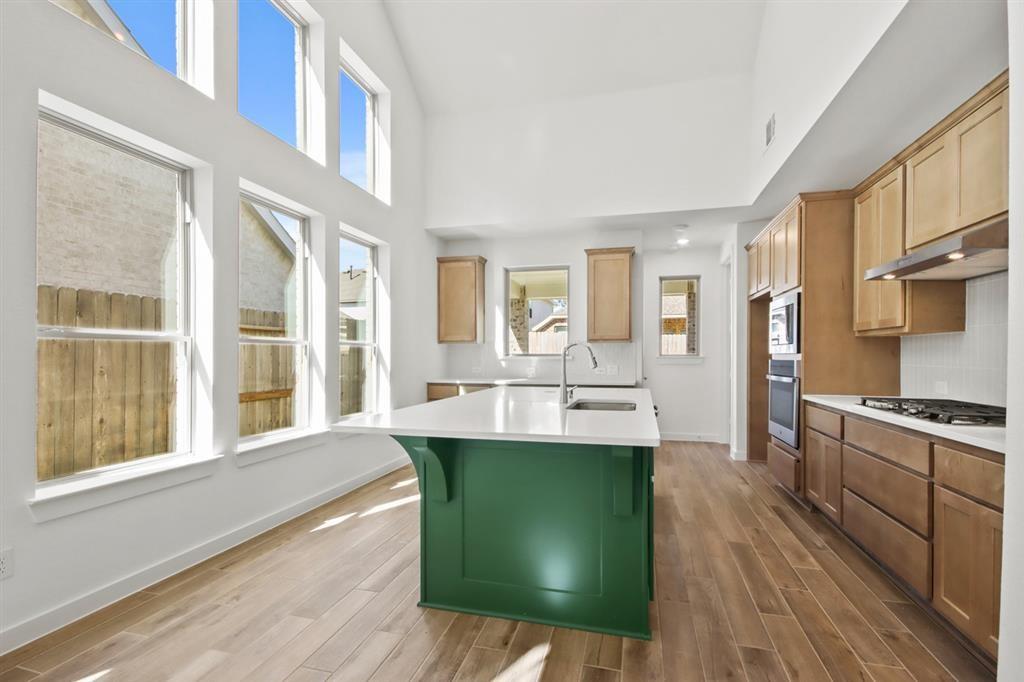 a view of a kitchen with kitchen island a large window a sink and stainless steel appliances