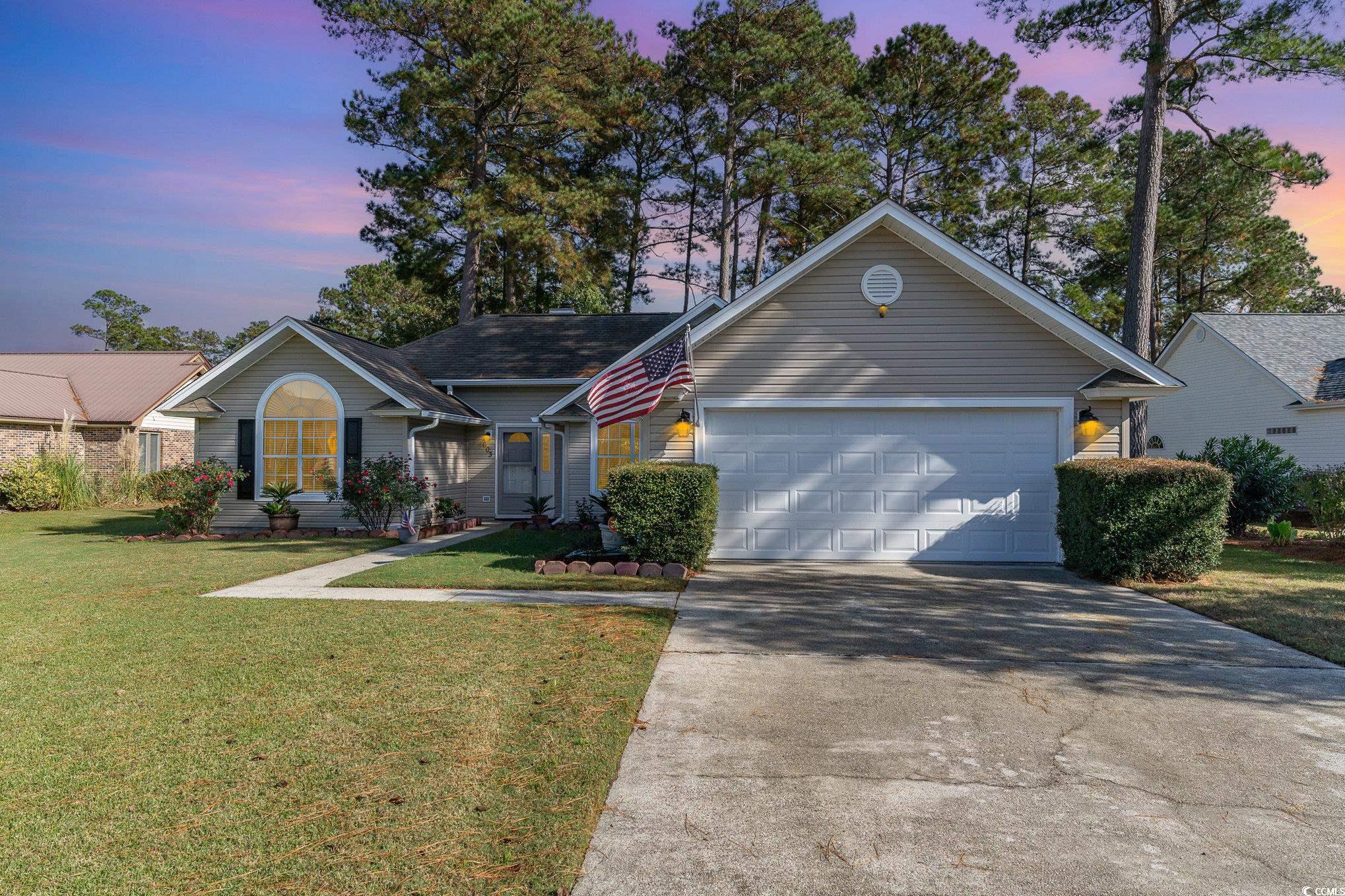 View of front facade featuring a garage and a yard