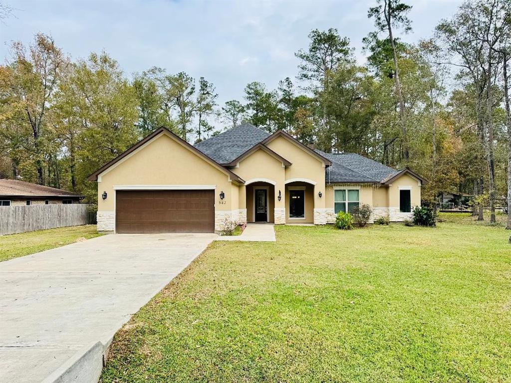 Beautiful stucco and stone home sits far off in the distance with a long driveway. Plenty of greenery blanket the home.