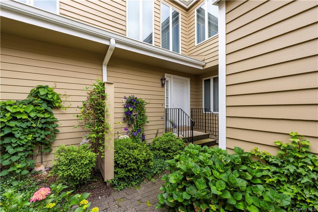 a yellow house with flower garden and wooden fence