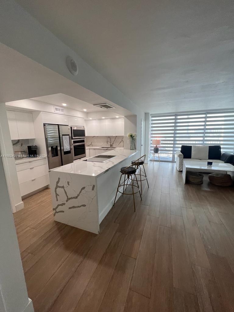 a large white kitchen with wooden floor and a sink