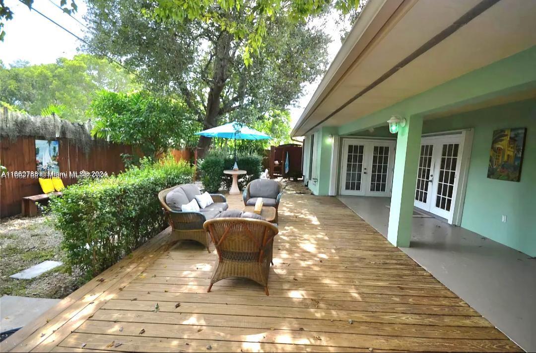 a view of a patio with table and chairs potted plants and floor to ceiling window