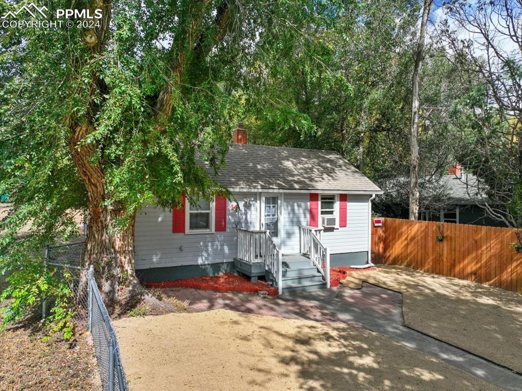 a view of a house with a yard and large tree