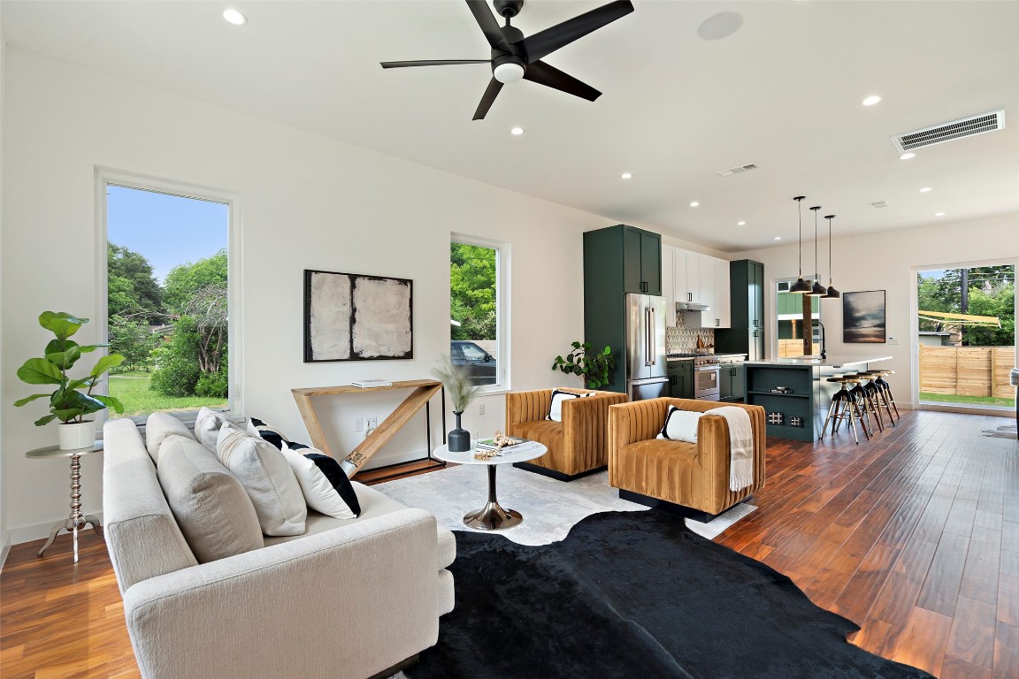 a living room with furniture kitchen view and a wooden floor