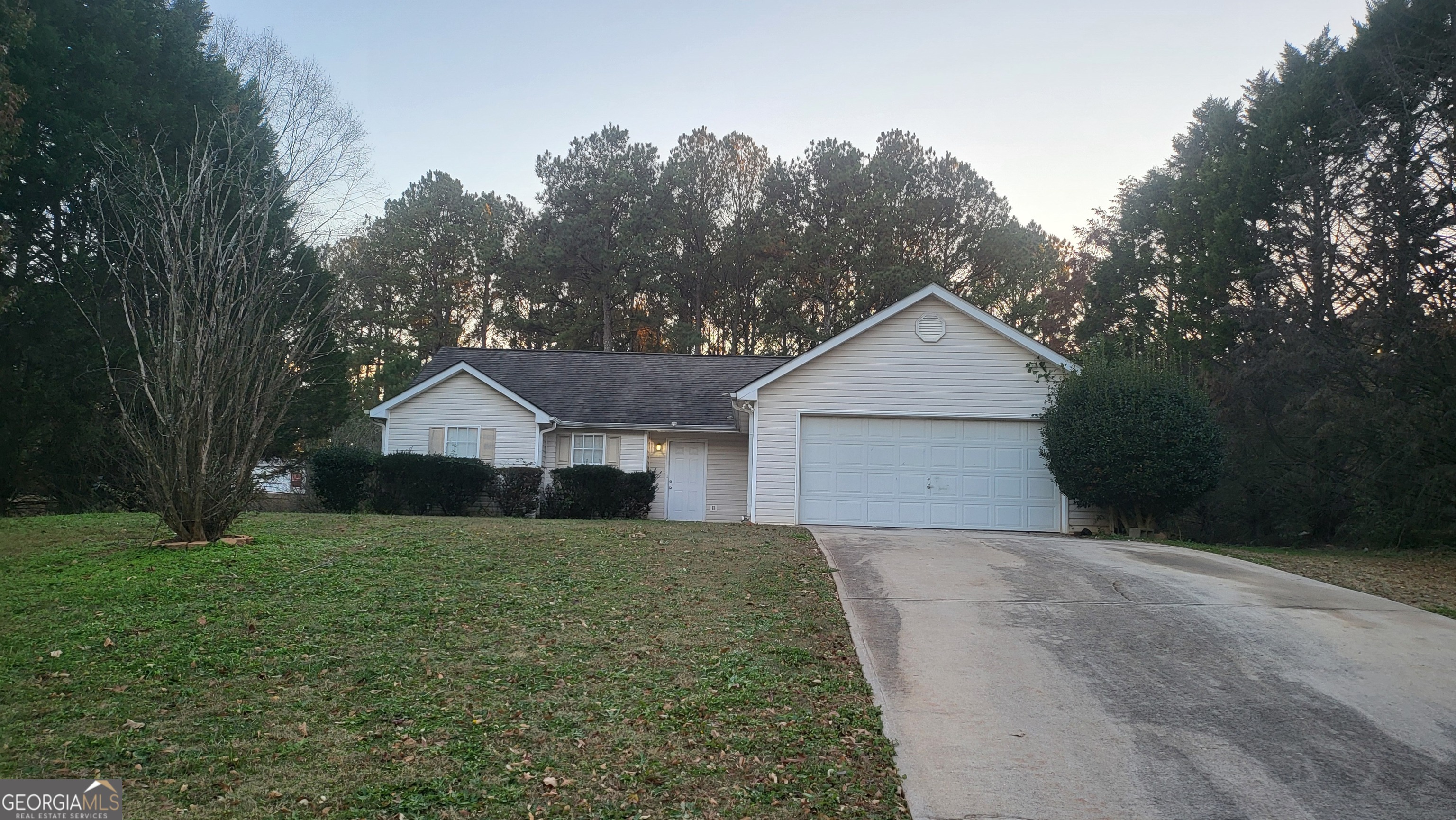 a view of a house with a yard and large trees