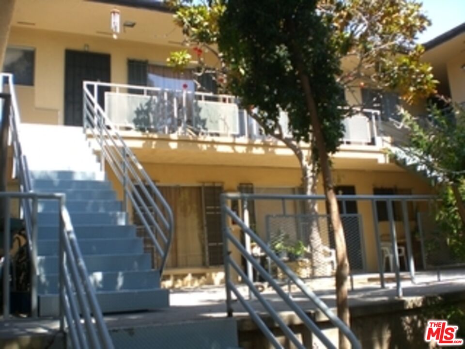 a view of a patio with table and chairs with wooden fence and large trees