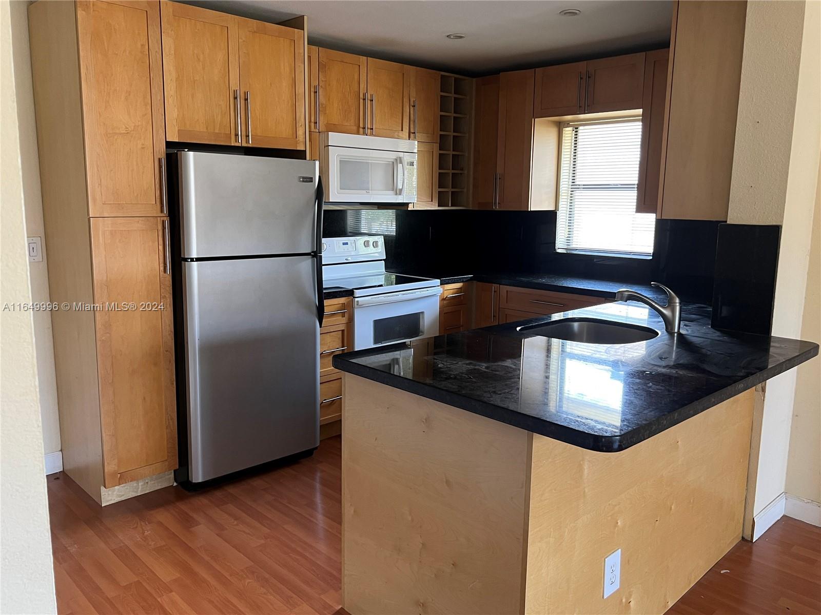 a kitchen with granite countertop a refrigerator and a stove top oven