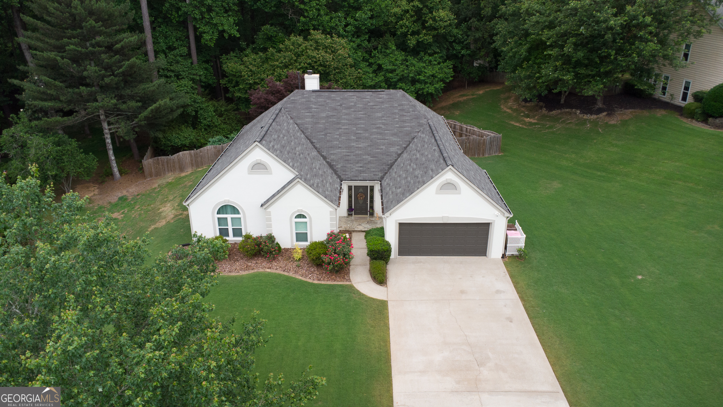 a aerial view of a house next to a big yard and large trees