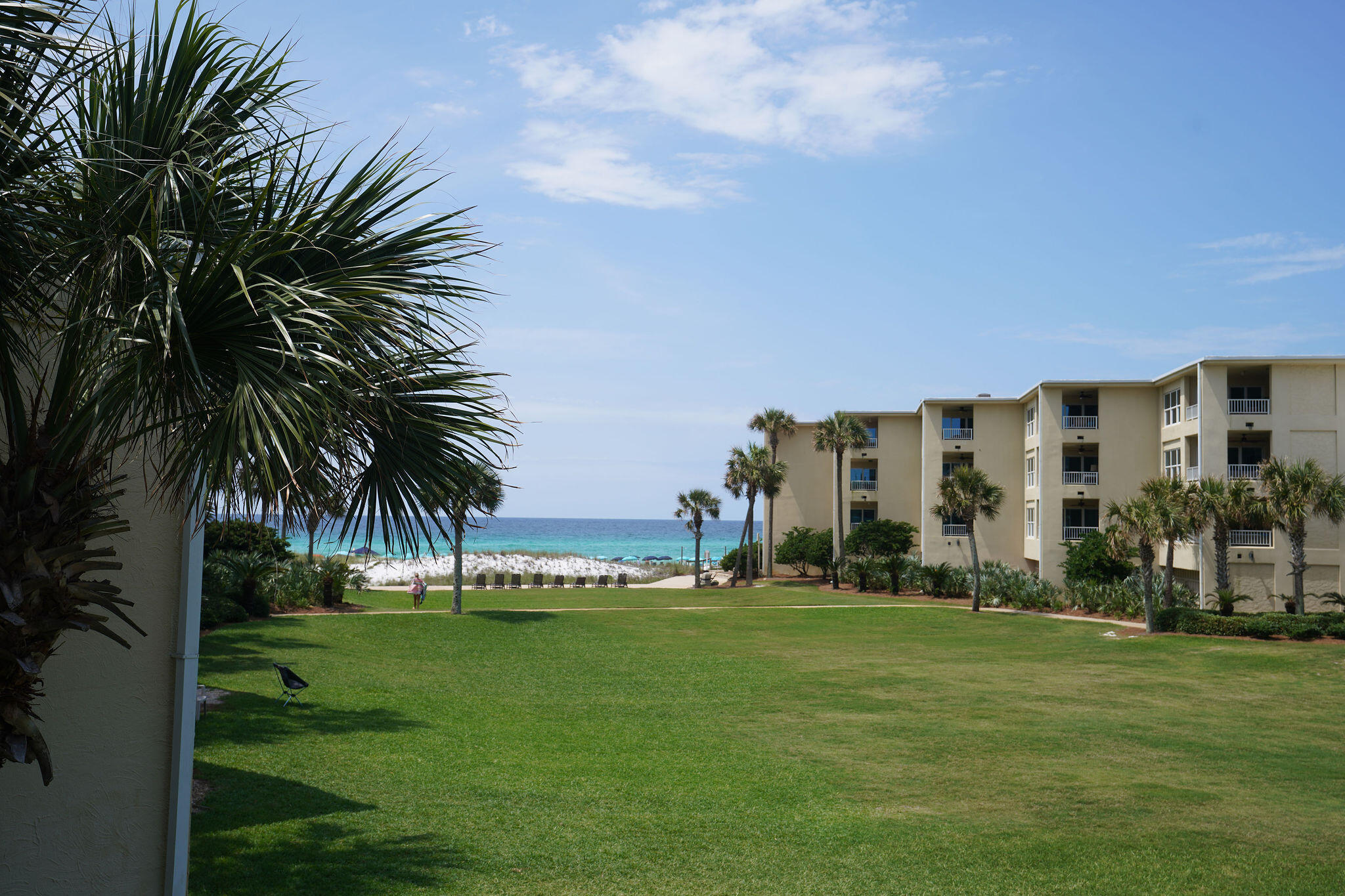 a view of a apartment with a big yard and palm trees