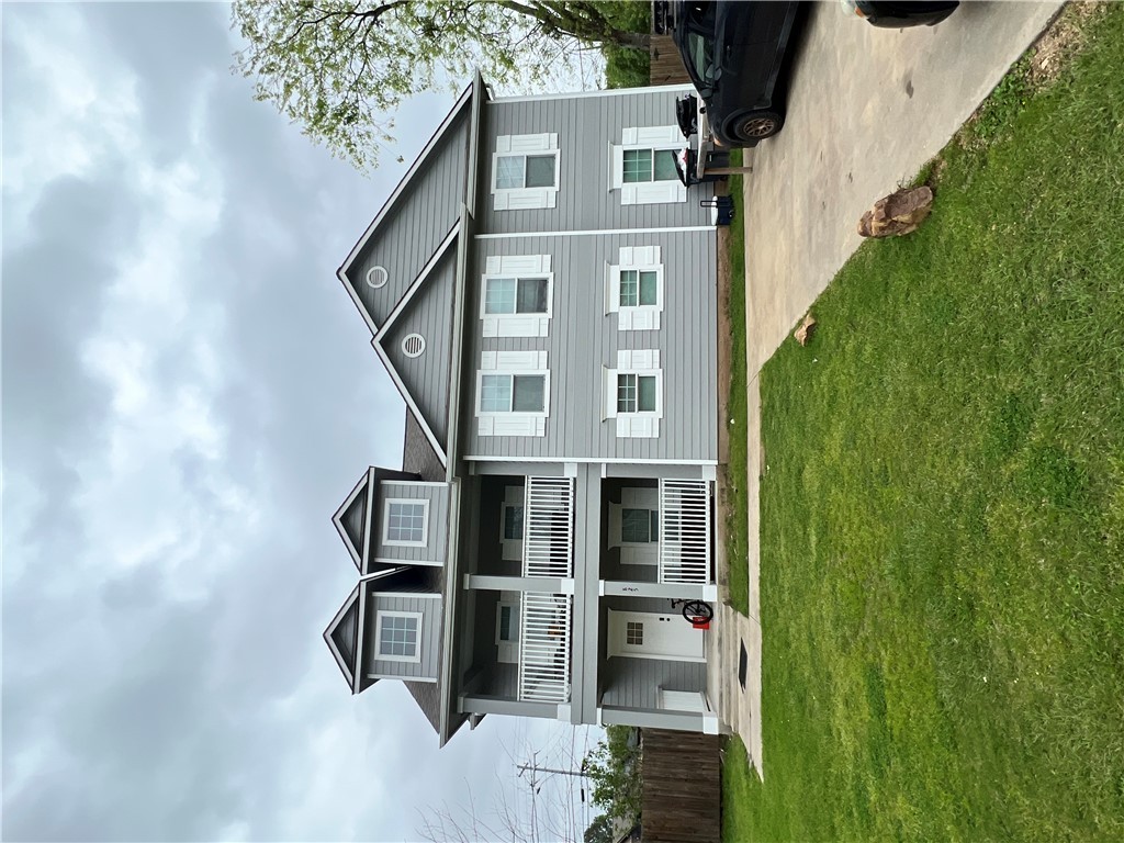 a front view of a house with a garden and lake view