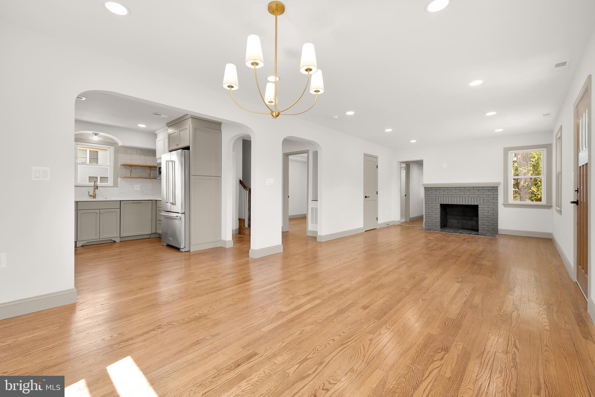 a view of a livingroom with a fireplace a chandelier and wooden floor