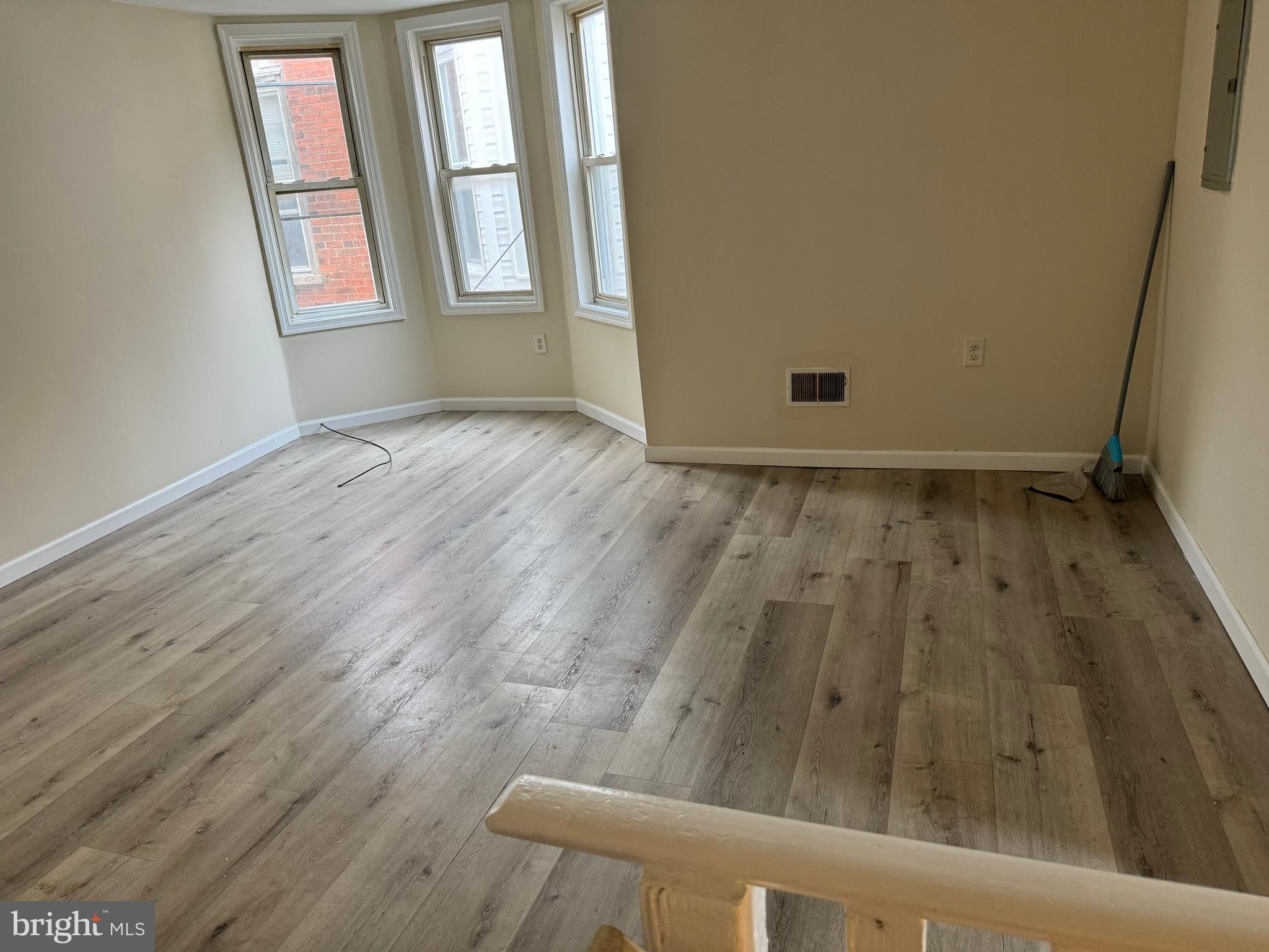 an empty room with wooden floor and windows