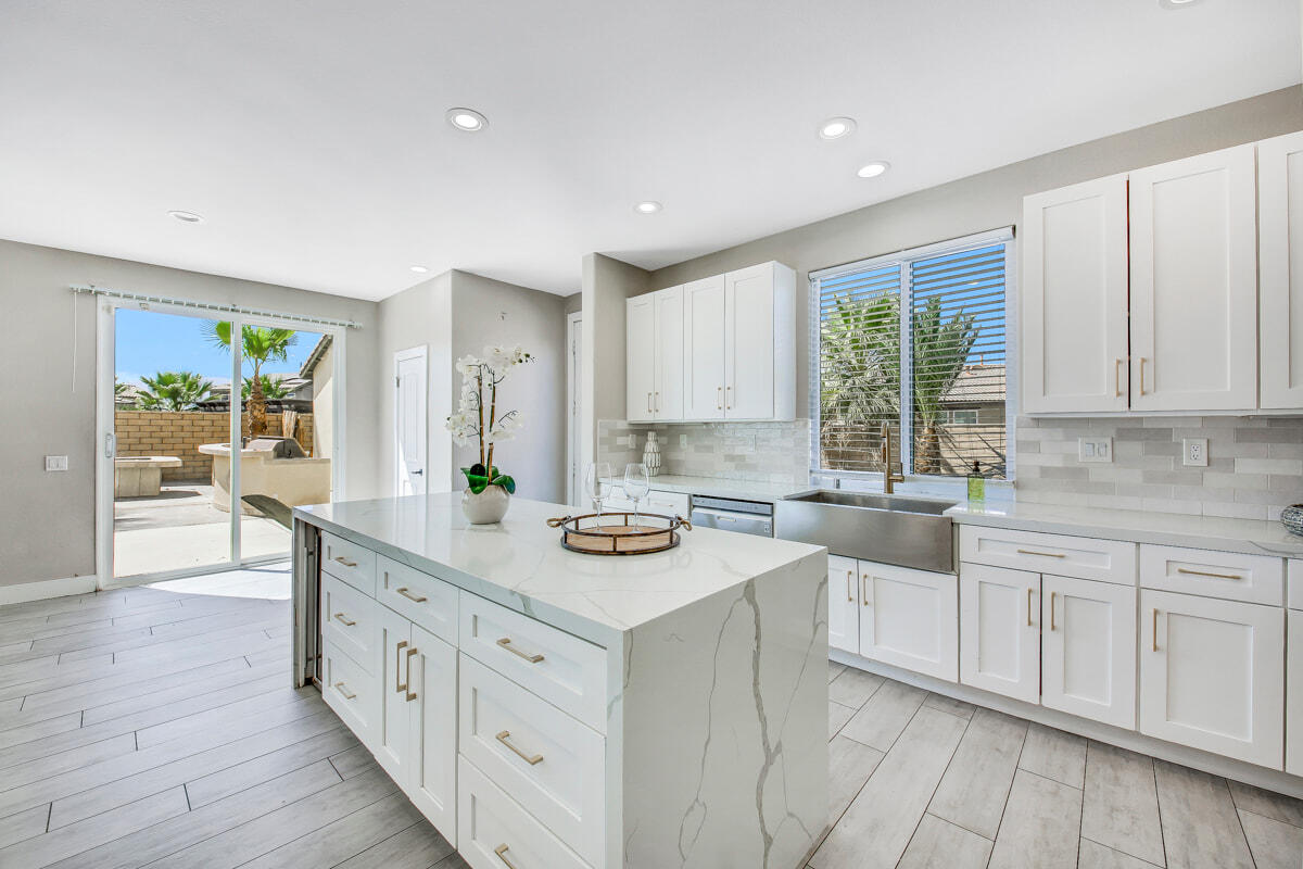 a kitchen with white cabinets a sink dishwasher and a stove with wooden floor