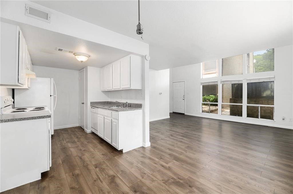 a kitchen with stainless steel appliances granite countertop a stove a sink and white cabinets with wooden floor