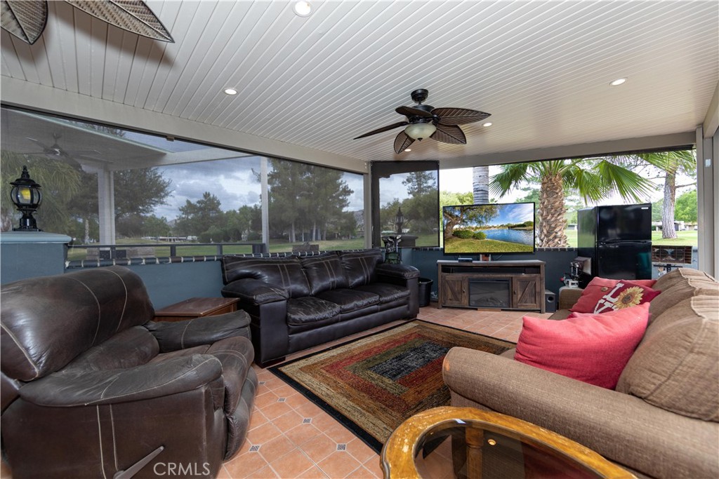 a living room with furniture a ceiling fan and a large window