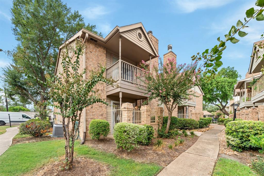 Beautiful brick condo with a cozy balcony and a private patio, surrounded by lush greenery and a peaceful walkway