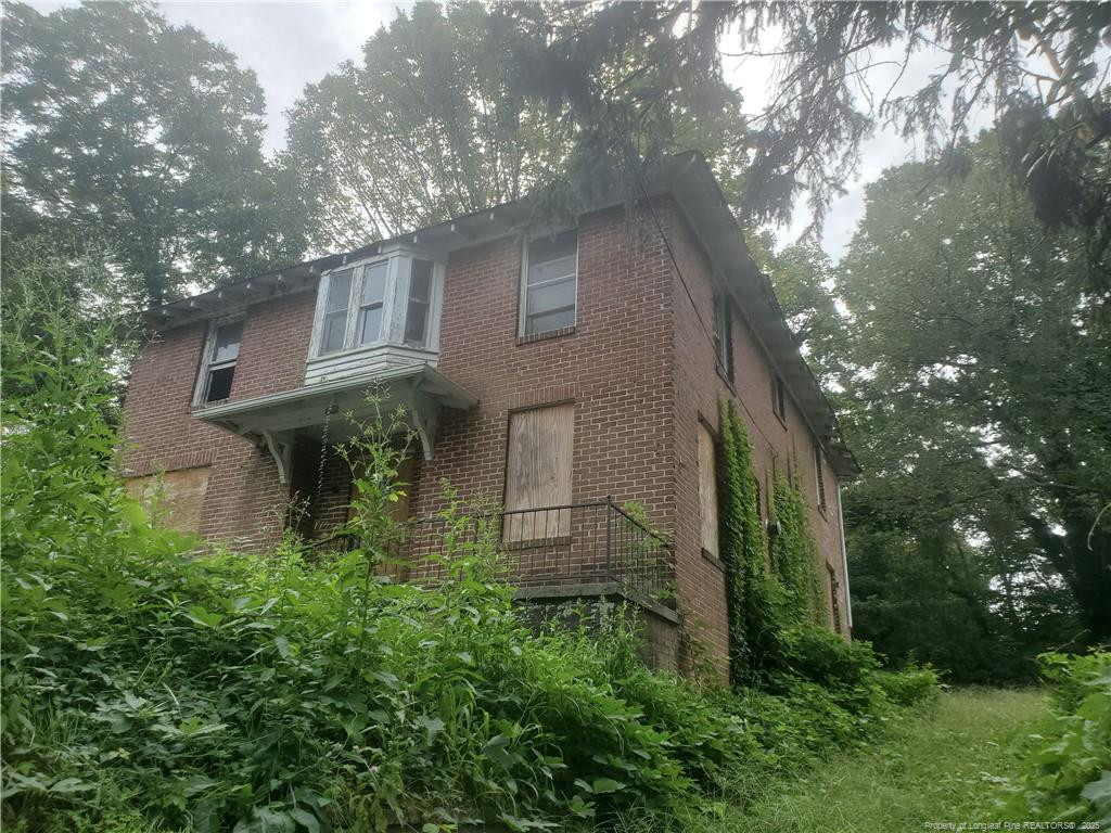 a backyard of a house with plants and large tree