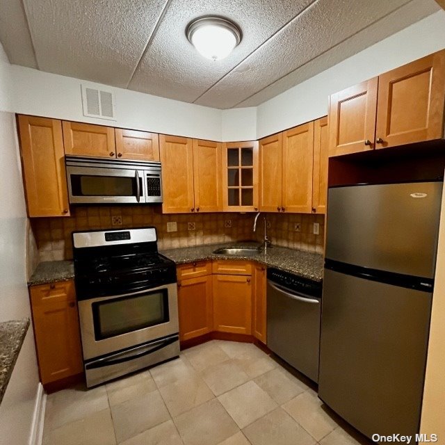 a kitchen with granite countertop a refrigerator and a stove top oven