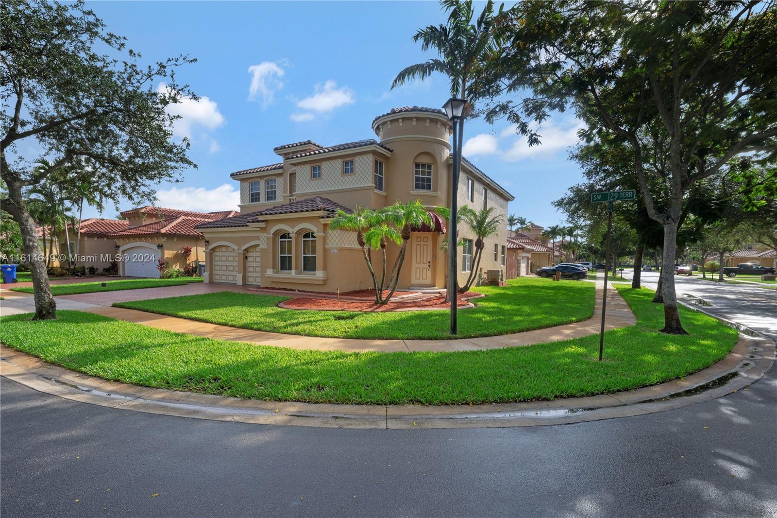 a front view of a house with a garden and trees