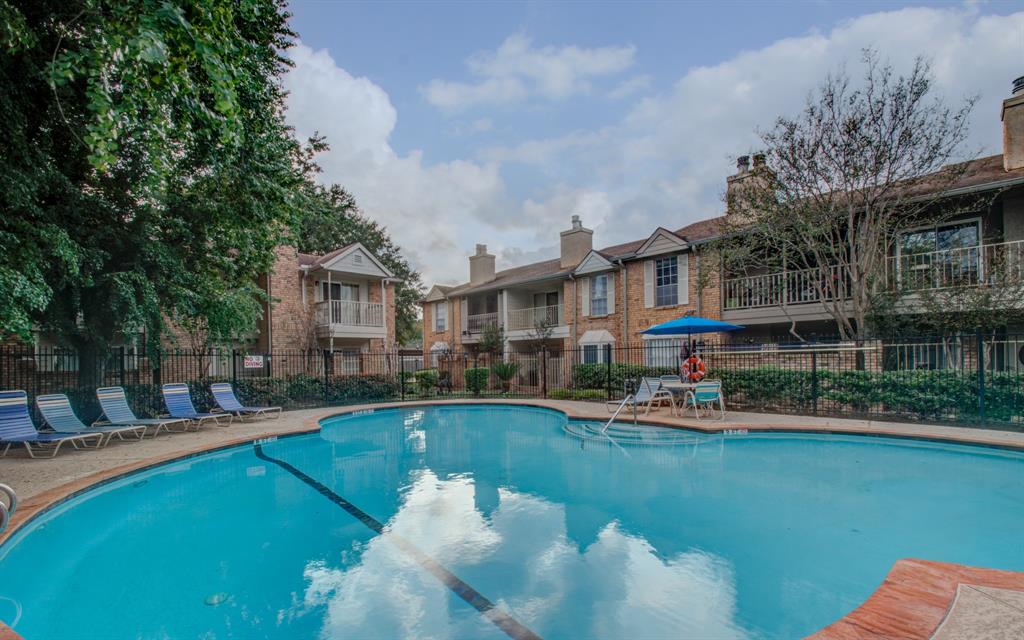 a view of a swimming pool with lounge chairs in front of house