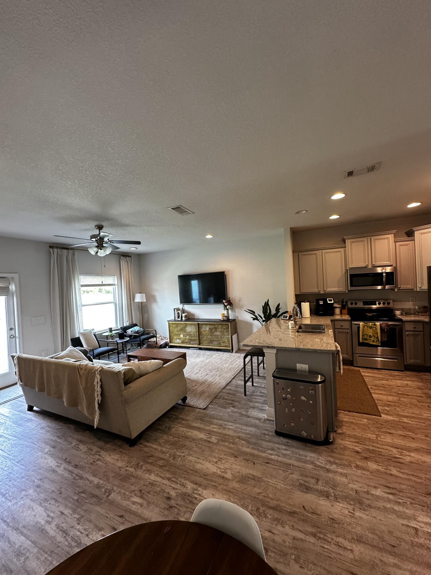 a living room with furniture kitchen area and a flat screen tv