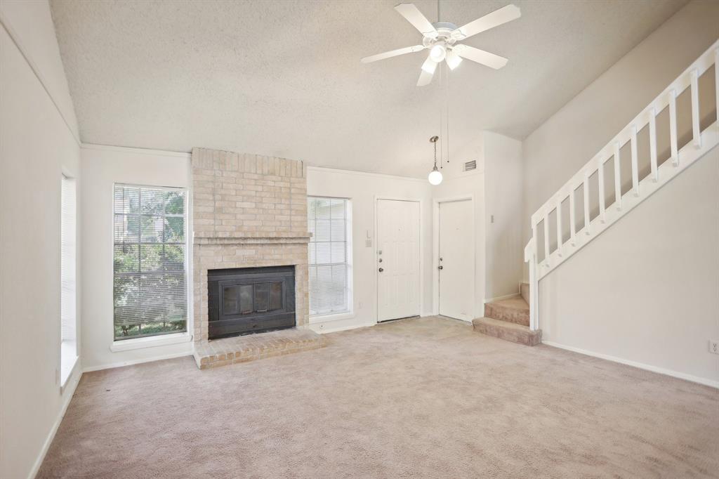 a view of an empty room with chandelier fan and fire place