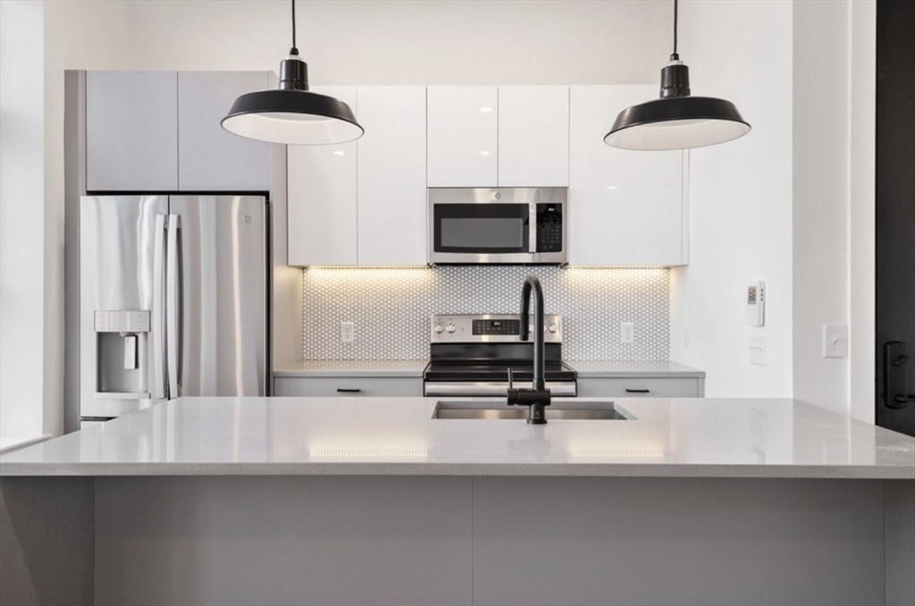 a kitchen with stainless steel appliances a microwave a stove and white cabinets