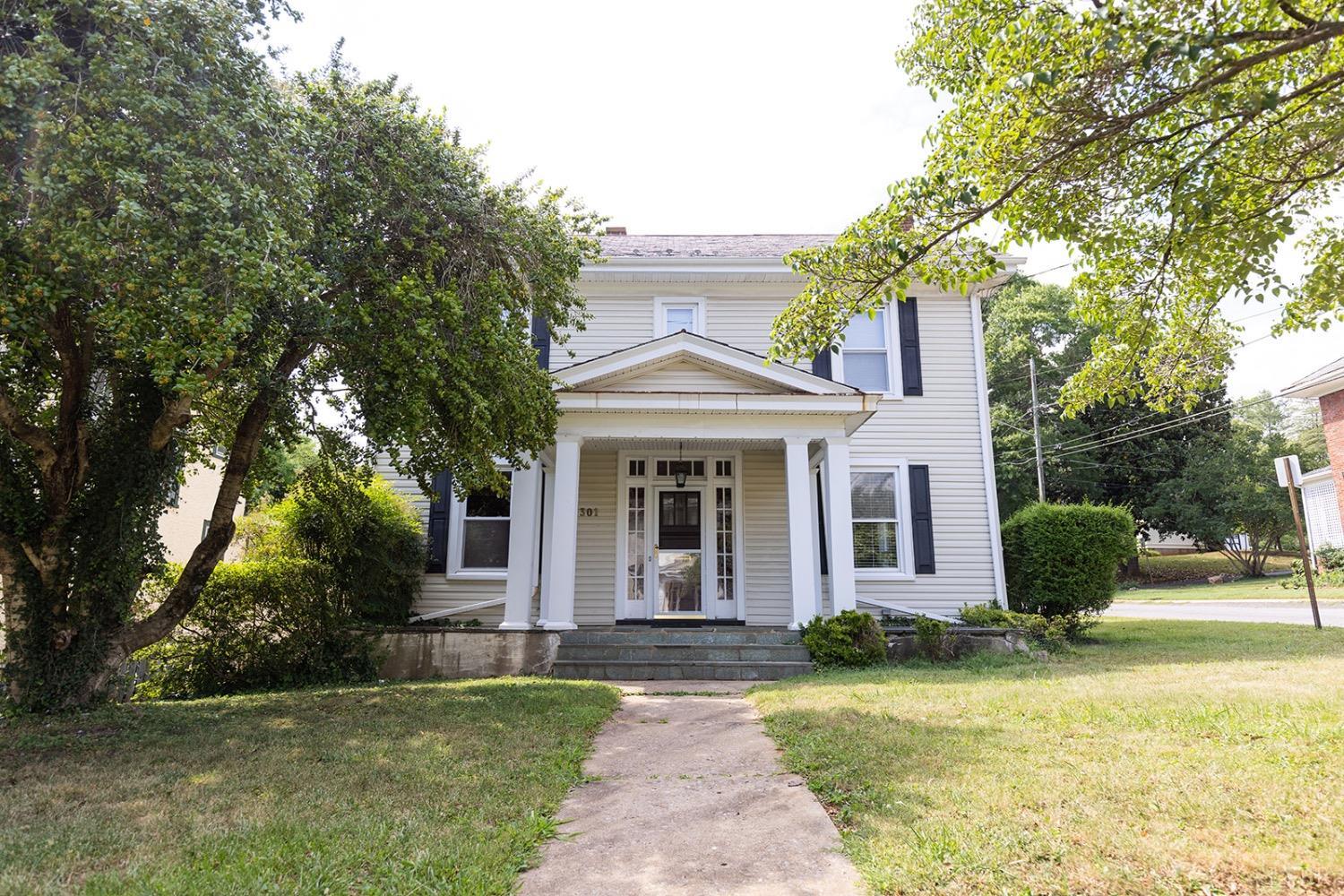 a front view of a house with garden and trees