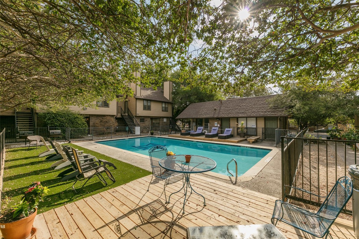 a view of swimming pool with lawn chairs under an umbrella