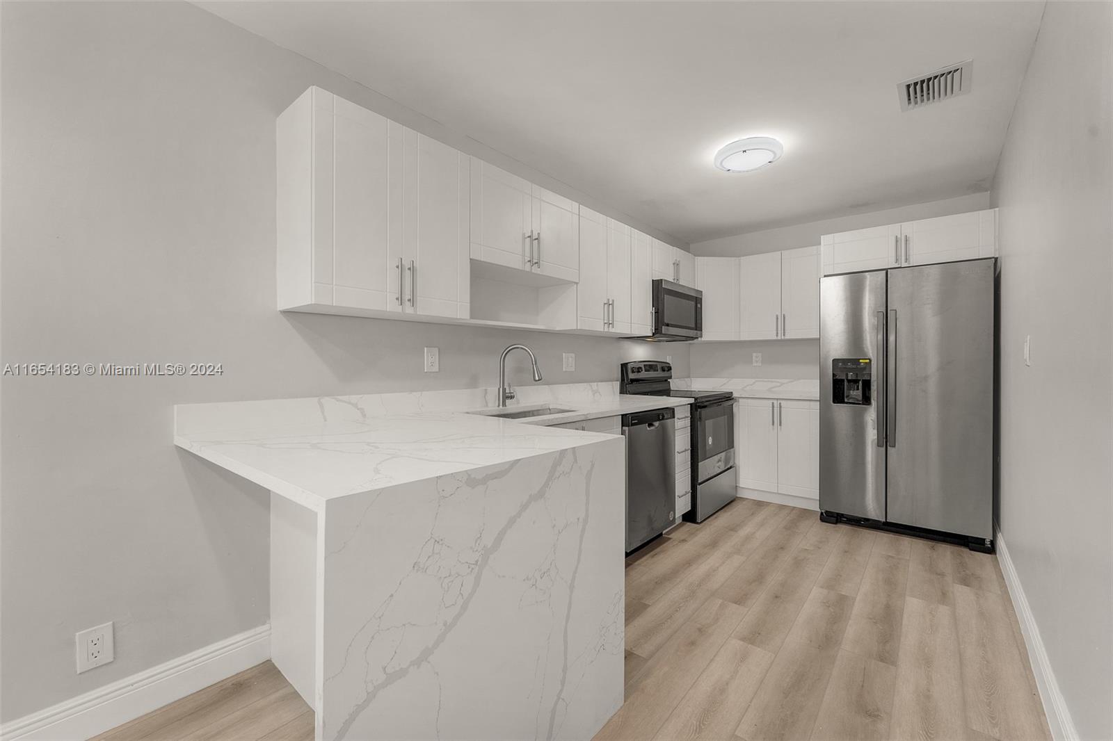 a kitchen with a sink a refrigerator and white cabinets