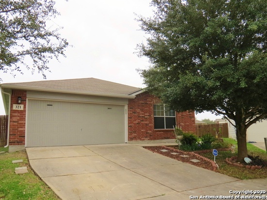 a front view of a house with yard garage and tree