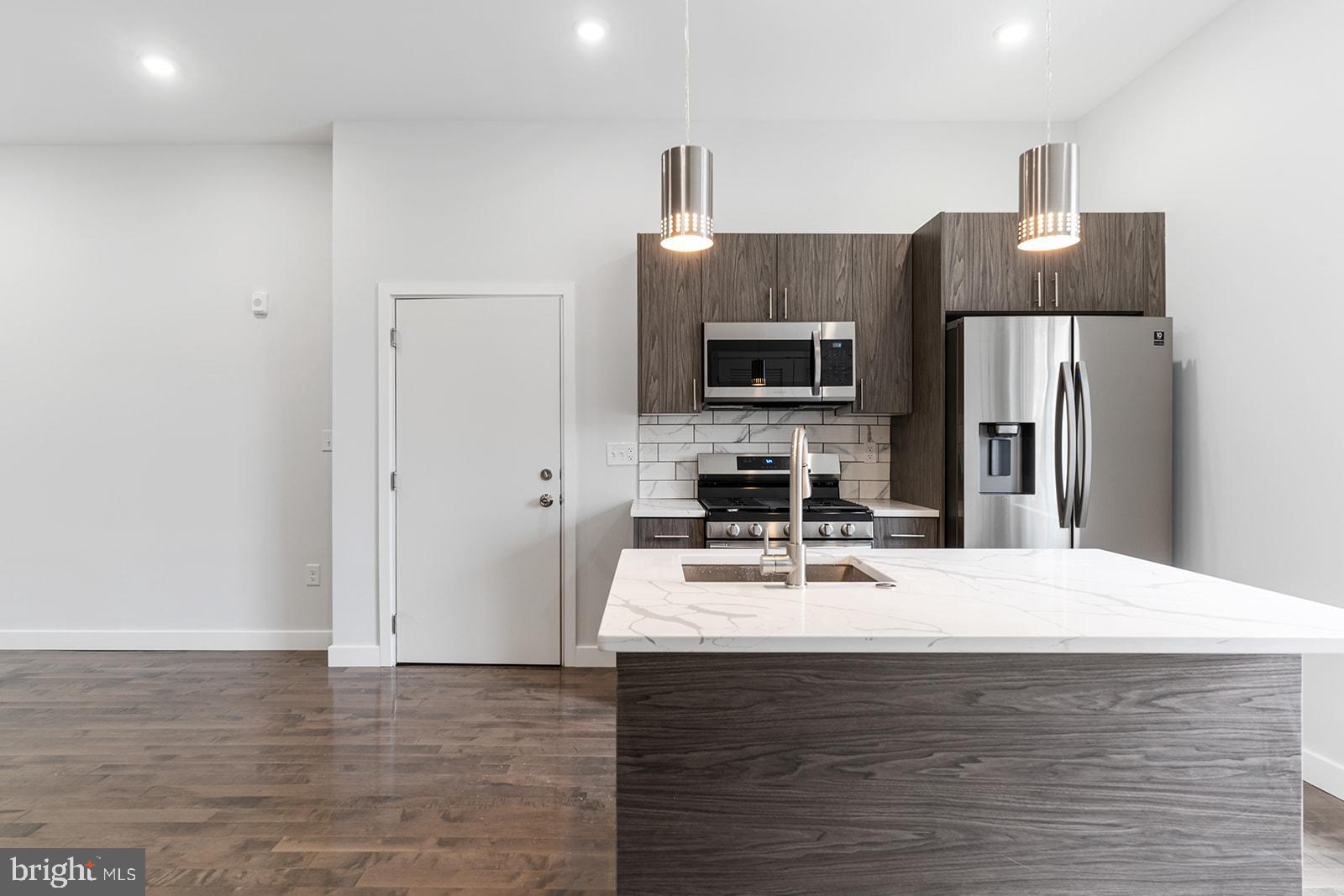 a kitchen with stainless steel appliances a refrigerator sink and microwave