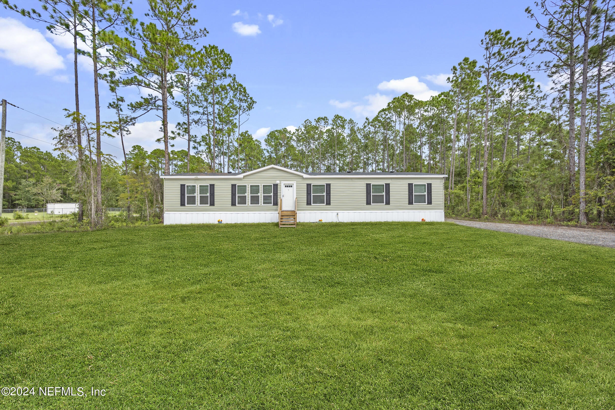 a view of house with yard and trees in the background