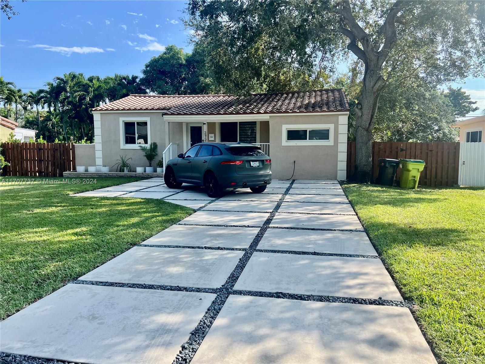 a front view of a house with a yard and potted plants