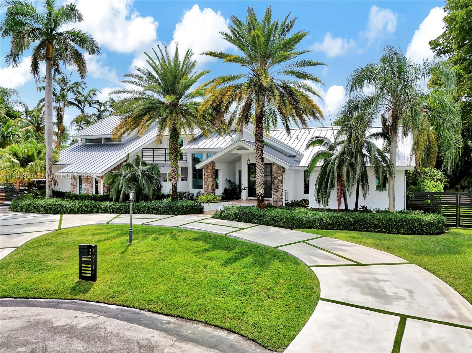 front view of a house with a yard and palm trees