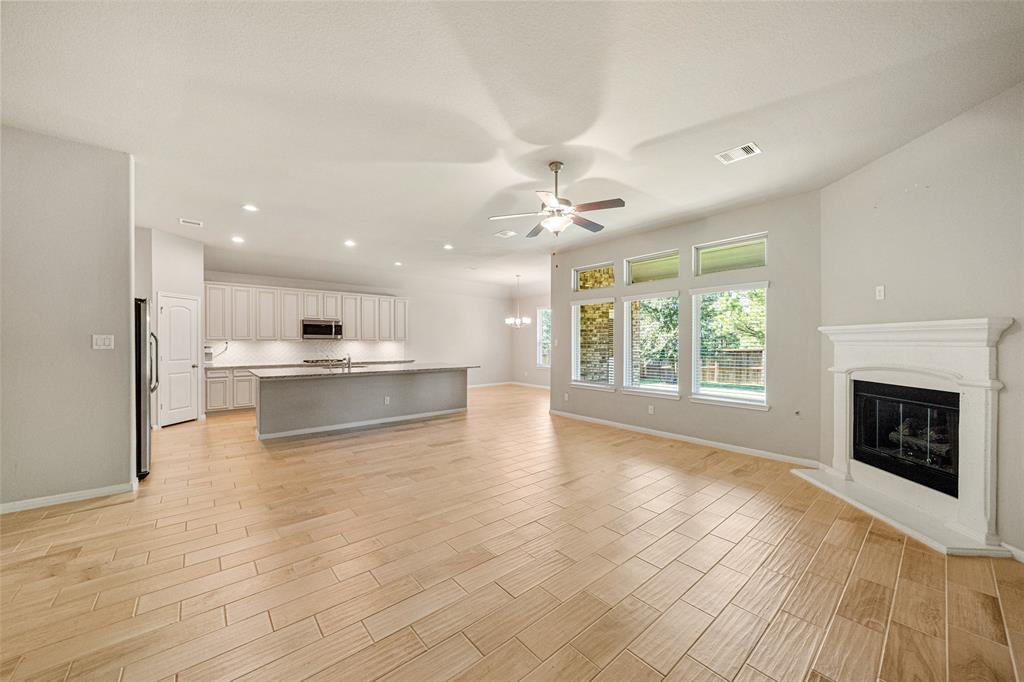 a view of an empty room with a kitchen and a fireplace