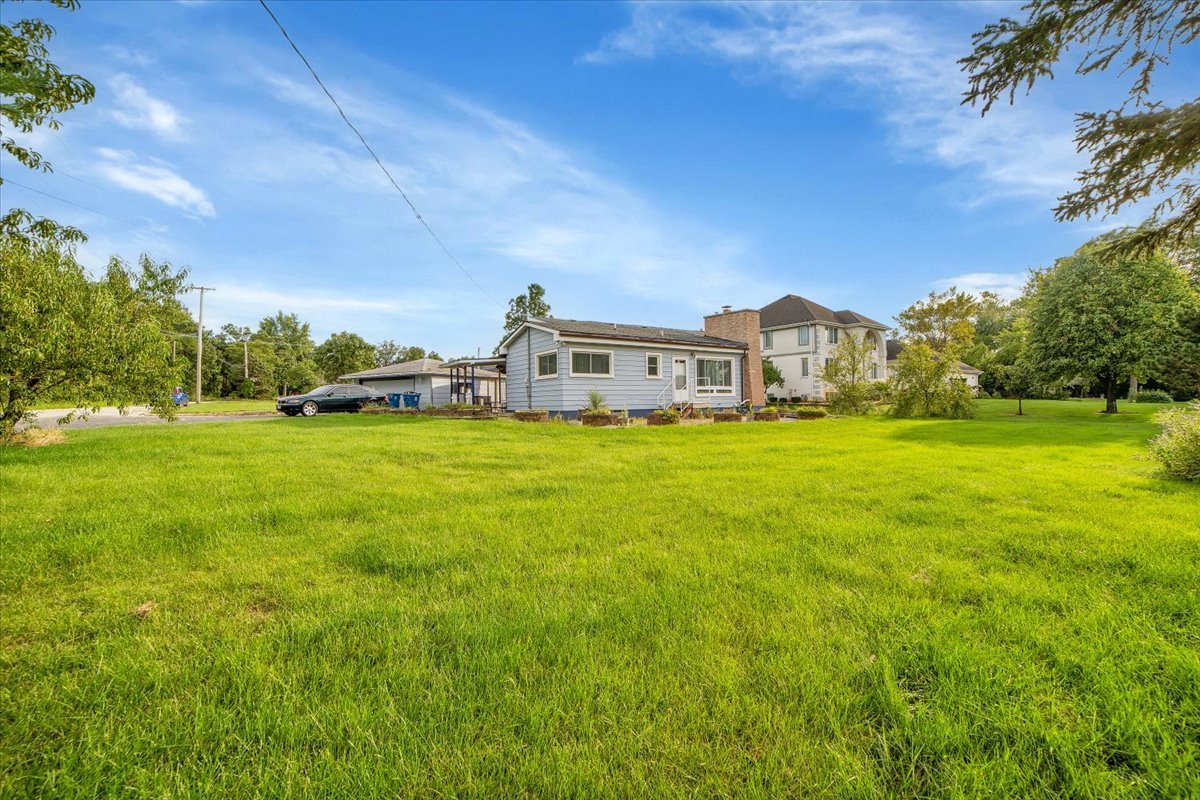 a view of a house with a big yard and large trees