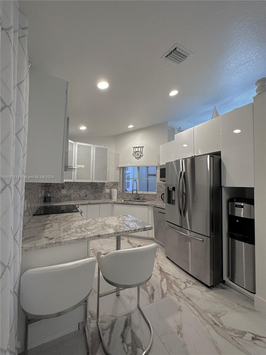 a kitchen with refrigerator and chairs