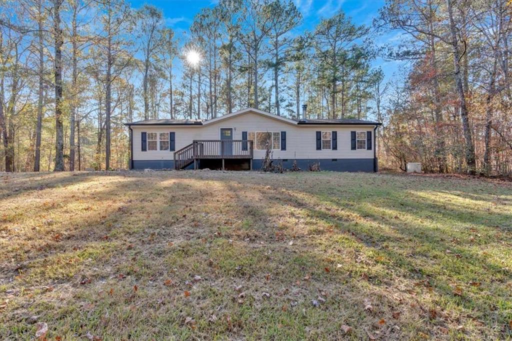 a house that is sitting in the grass with large trees and wooden fence