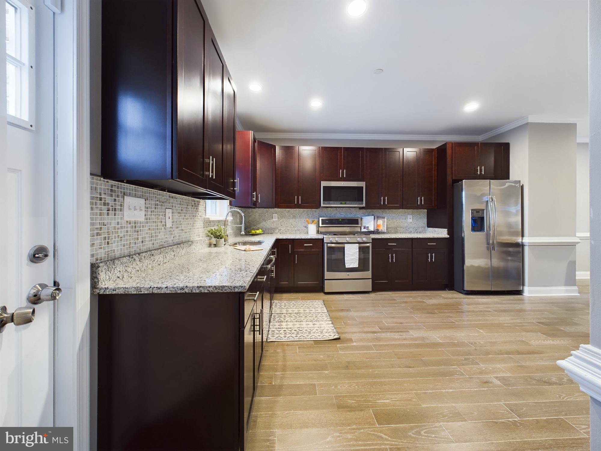 a kitchen with stainless steel appliances granite countertop a sink refrigerator and cabinets