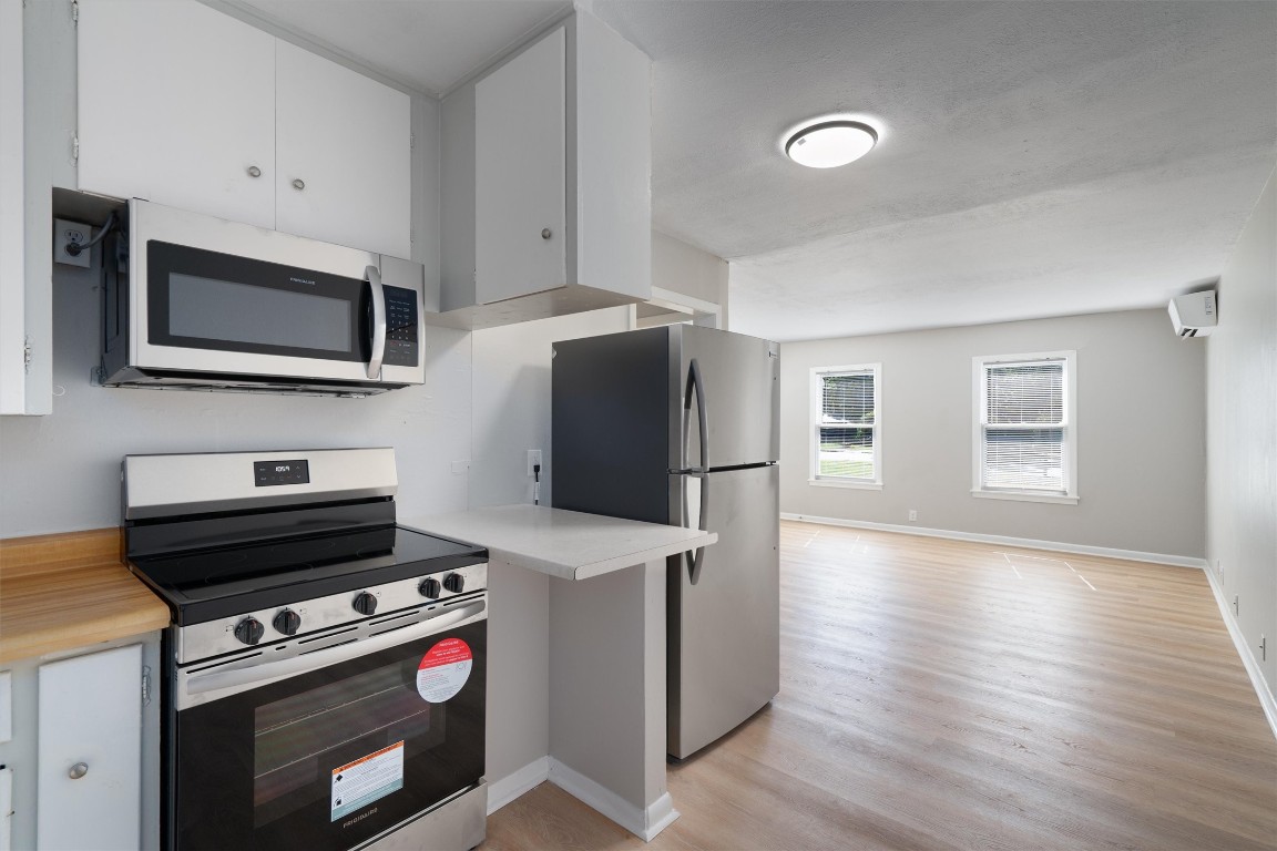 a kitchen with stainless steel appliances a stove a microwave and a hard wood floors