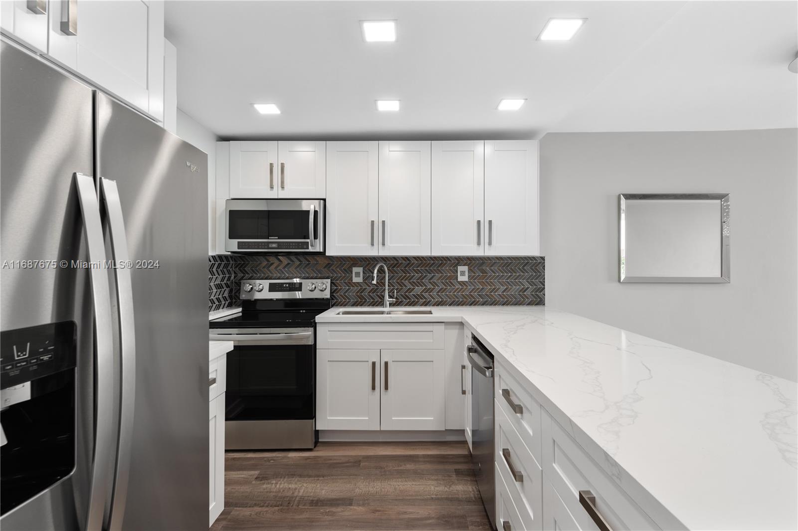 a kitchen with a sink a refrigerator and a stove top oven with wooden floor