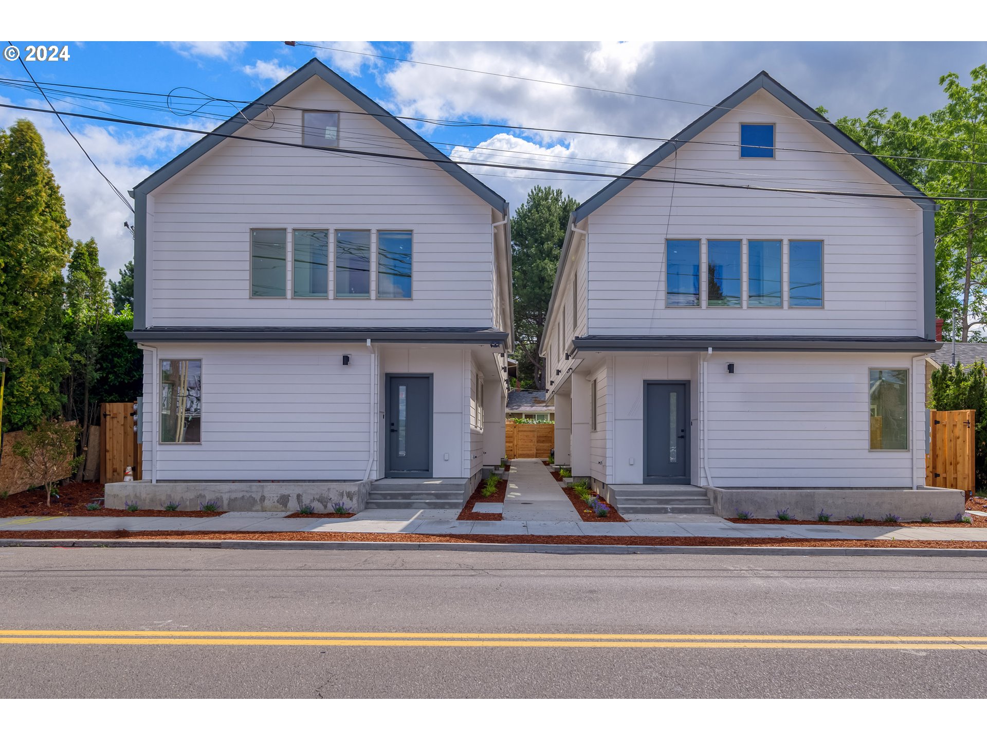 a view of a house with a small yard and large parking space