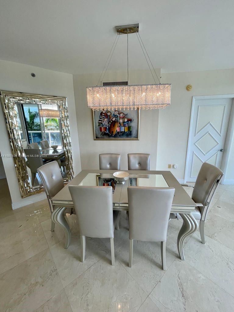 a view of a dining room with furniture a chandelier and window