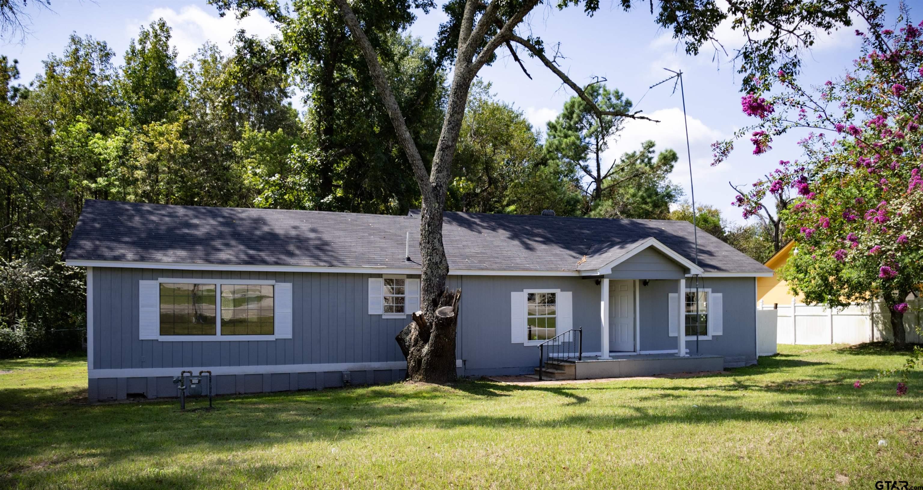 a view of a yard in front of house with a large tree