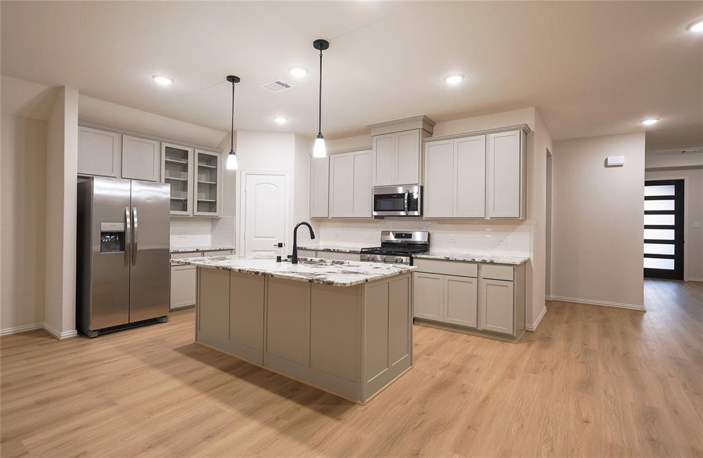 a kitchen with stainless steel appliances granite countertop a refrigerator a sink dishwasher a stove and a wooden floors