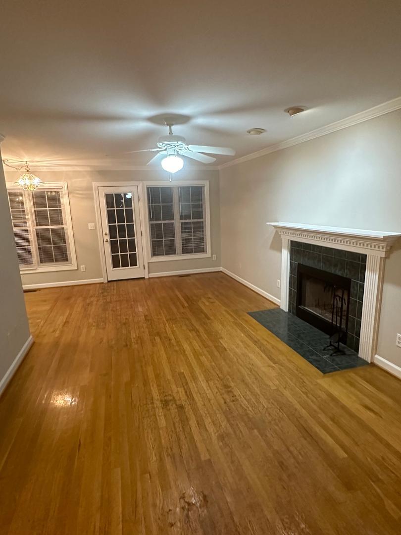 a view of an empty room with wooden floor and a fireplace