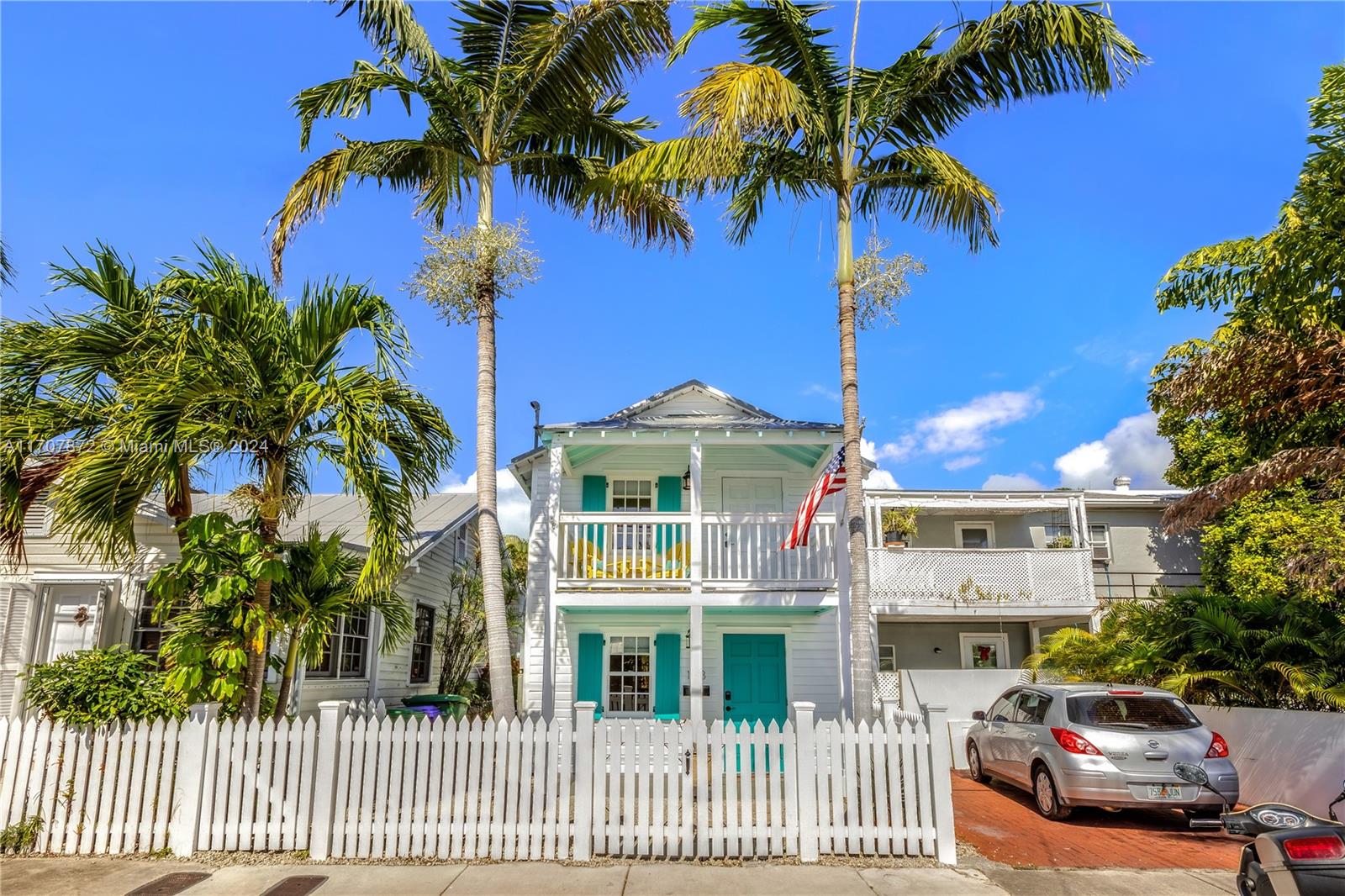 a front view of multiple houses with palm trees